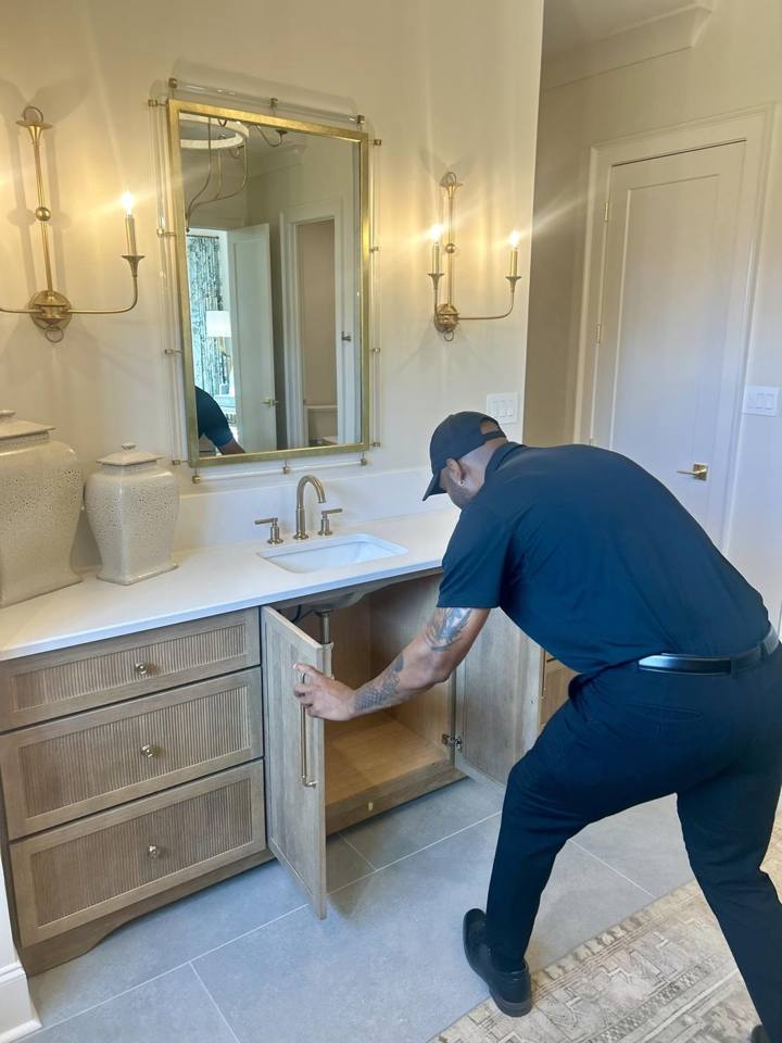 David Clark examining accessible bathroom plumbing during a home inspection